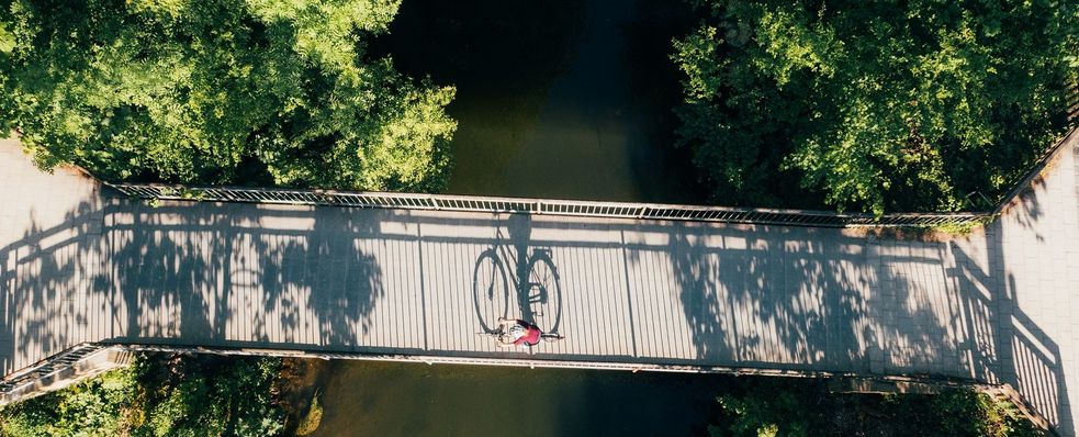 Ein Symbolbild für die Radwege auf dem Dachauer Stadtgebiet: Radfahrer auf Brücke, von oben fotografiert.