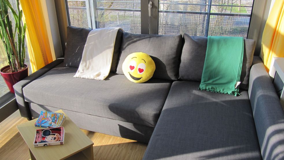 Graues Ecksofa mit Smiley-Kuscheltier und Decken