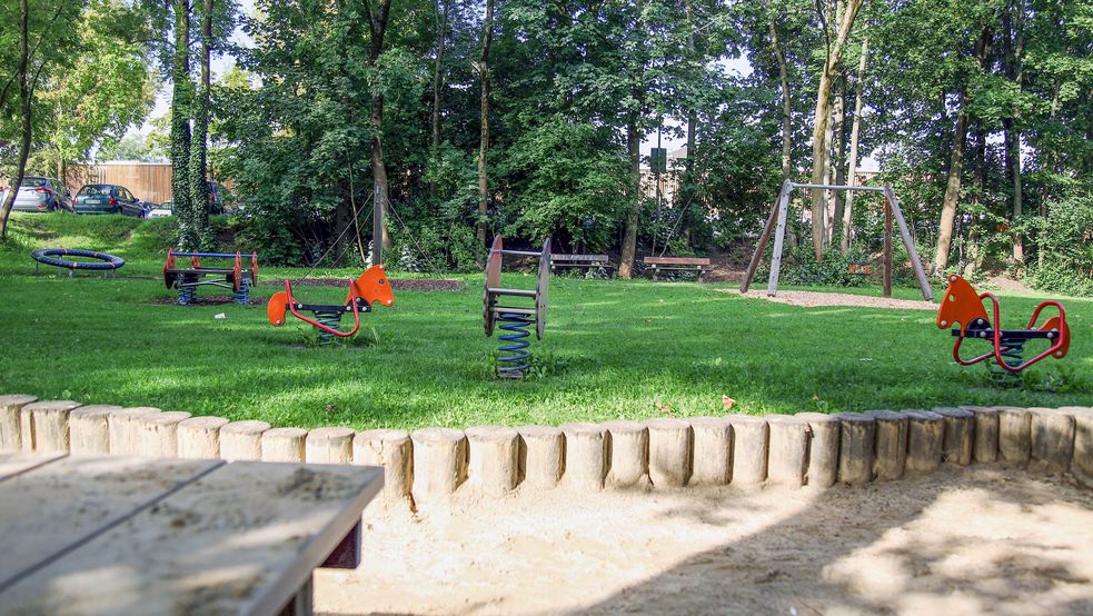 Schaukelpferde auf dem Rasen neben einem Sandkasten