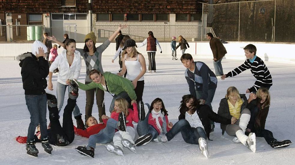 Eine Gruppe Jugendlicher in Schlittschuhen auf der Eisbahn