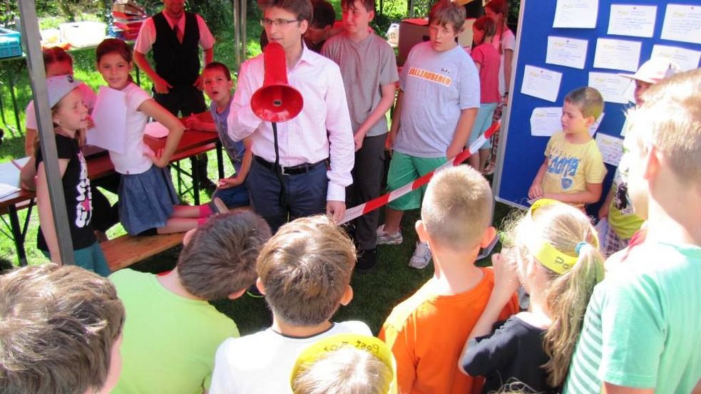 Oberbürgermeister Florian Hartmann spricht ins Megafon zu einer Menge Kinder im Publikum