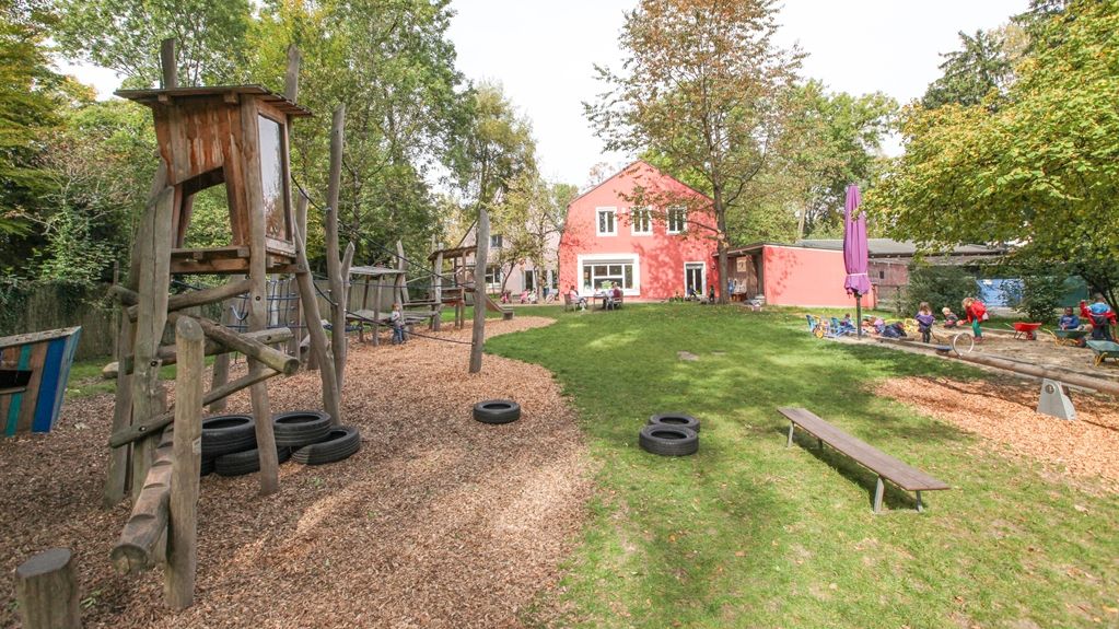 Spielplatz im Grünen mit Haus im Hintergrund