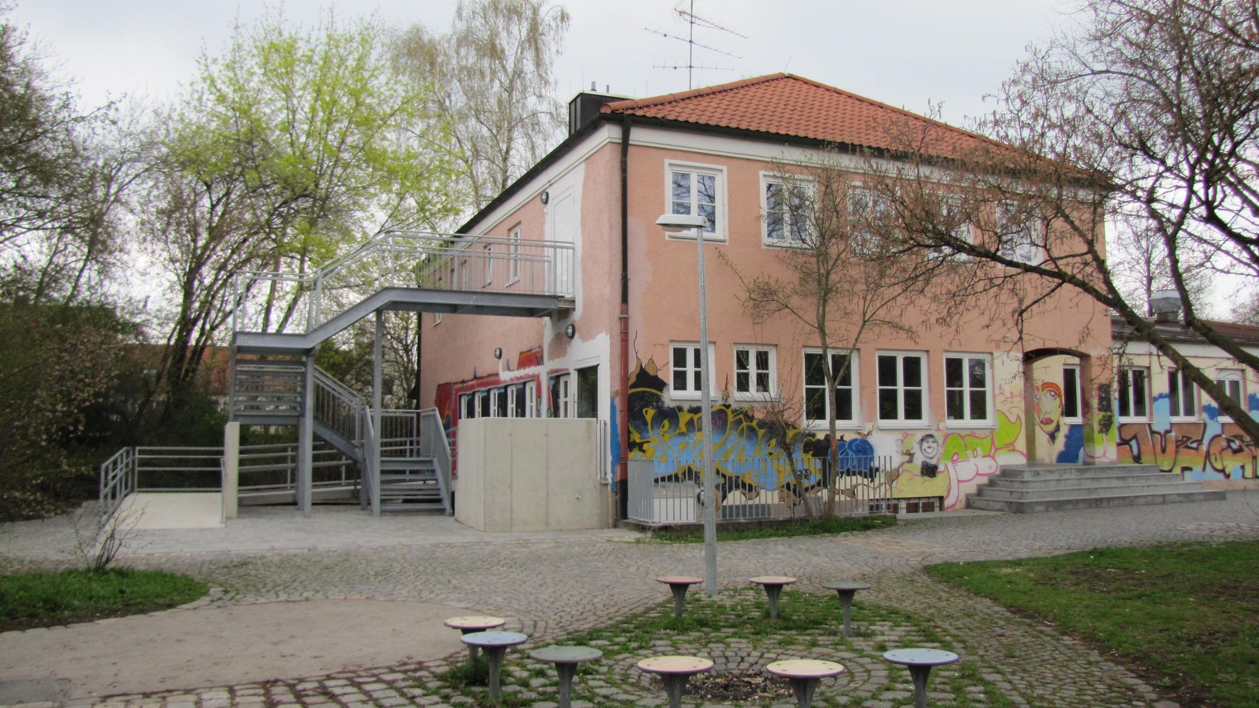 Jugendzentrum Ost mit Graffitifassade und Sitzmöglichkeiten im Vordergrund