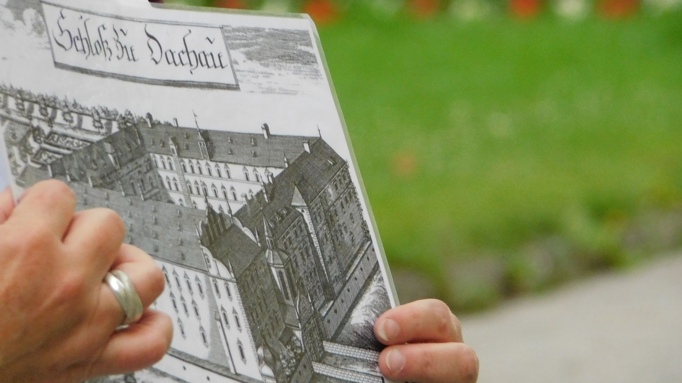 Foto-Ausschnitt Stadtführung, Gästeführerin zeigt historische Ansicht des Dachauer Schlosses