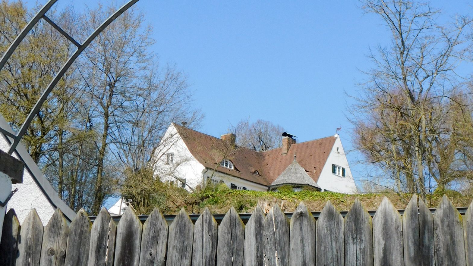 Fotografie der ehemaligen Taschner Villa vom Zaun aus durch einen Metall-Rosenbogen fotografiert.